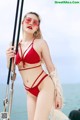 A woman in a red bikini standing on a boat.