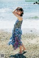 A woman standing on a beach next to the ocean.