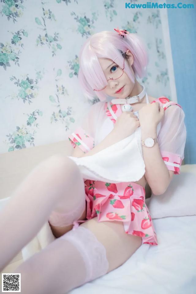 A woman in a pink outfit is sitting on a bed.
