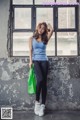 A woman standing in front of a window holding a green bag.