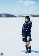 A woman in a school uniform standing in the snow.