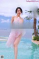 a woman in a pink dress standing next to a pool