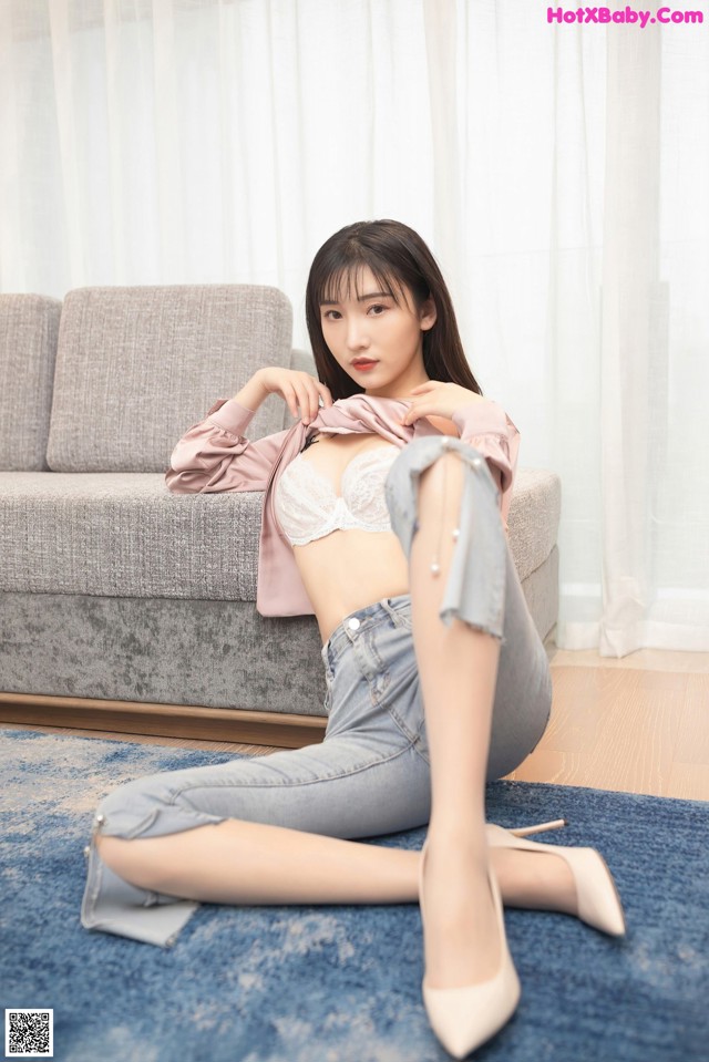 A woman sitting on a blue rug in front of a couch.
