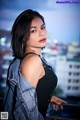 A woman in a black top and denim jacket posing for a picture.