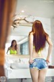 A woman in a yellow bikini standing in front of a mirror.