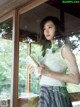 A woman standing in front of a window holding a book.